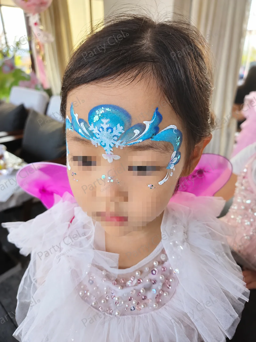 페이스페인팅 전문가가 아이 이마에 파란 눈꽃 도안을 그려 완성한 모습