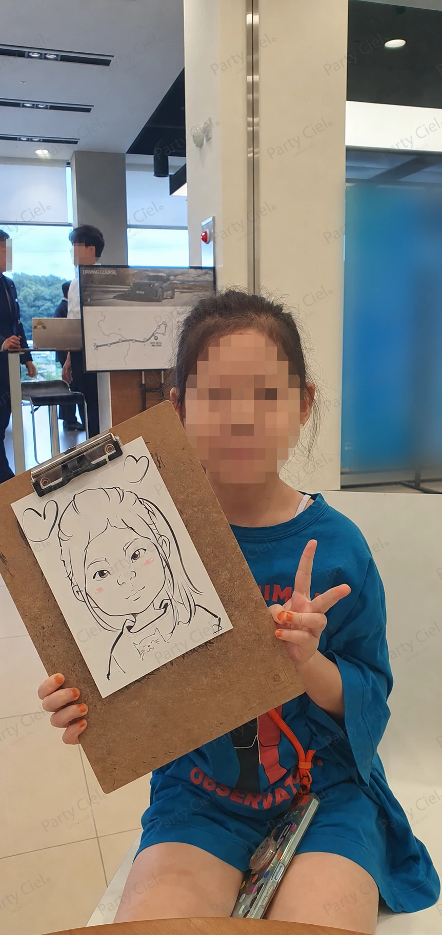 전시장에서 완성된 캐리커처를 들고 있는 어린이 방문객