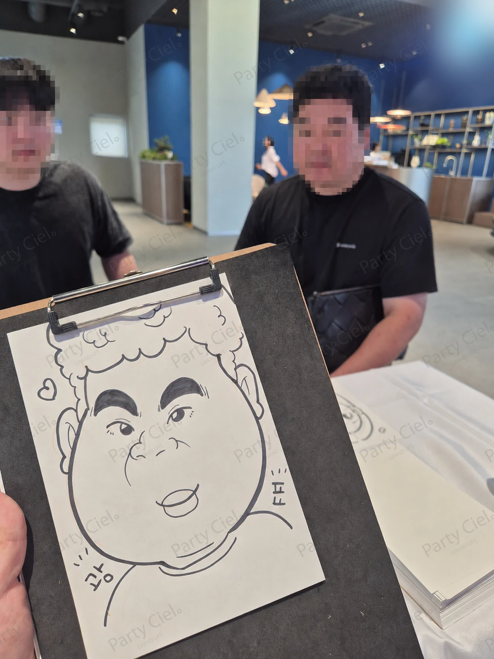 수입차 전시장에서 완성된 캐리커처 결과물을 보여주는 모습