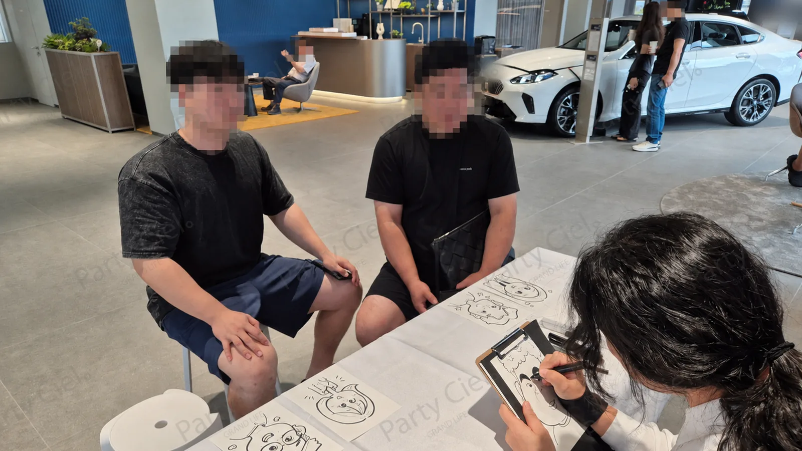 수입차 전시장에서 캐리커처 작가가 상담을 기다리는 방문 고객을 그려주는 모습