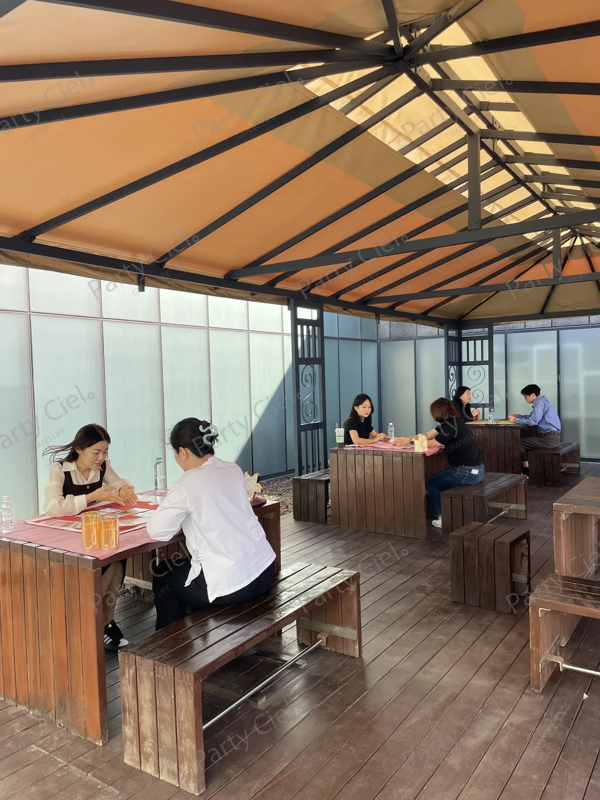 교보문고 파주 본사 테라스 천막 정자 아래 목재 테이블 세 자리에서 타로 상담이 동시에 진행되는 모습